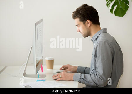 Focused businessman working on computer with project statistics, Stock Photo