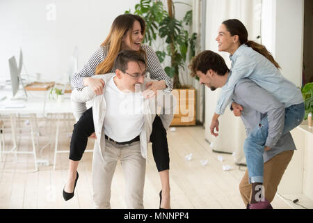 Happy colleagues having fun together enjoying piggyback ride in  Stock Photo