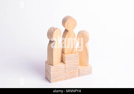 Three wooden figures of a man stand on the podium of the winners. The concept of victory, business competition and competition among employees. Olympi Stock Photo