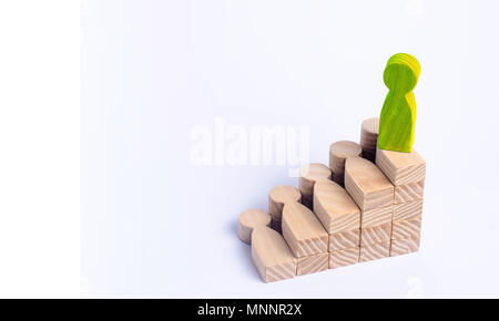 A green man stands at the top of a social or career ladder. Concept of business success. Stairs of people. Use other workers. A wooden figure of a man Stock Photo