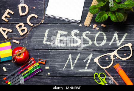 The inscription is lesson number one on the background of a school board, a table made of wooden dark boards. Top view. The concept of education, coop Stock Photo