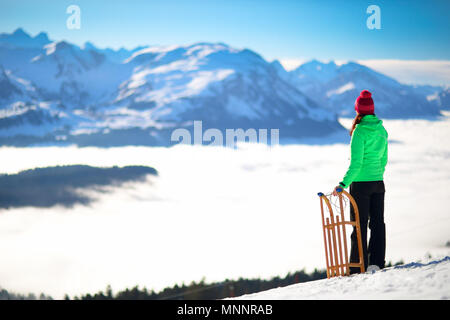 Young attractive woman ready to go sledding in Alps during winter holiday. Stock Photo