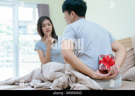Making a surprise ,Romantic man hiding a gift box behind his back surprising his girlfriend Stock Photo