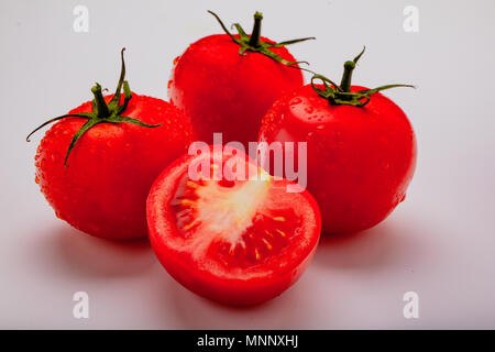 Three wet tomatoes plus one cut open Stock Photo