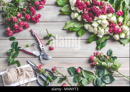 Red and white rose bush on a wooden table. Workplace florist. Top view Stock Photo