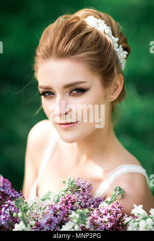Portrait of beauty bride in white dress. The bride is holding a wedding bouquet of lilacs Stock Photo