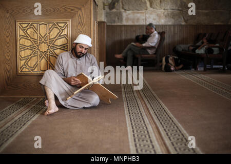 Idlib, Syria. 18th May, 2018. A Syrian Muslim man who has been evacuated from the rebel-held area of Homs, reads verses of Quran, Islam's holy book, at the Great Mosque of Maarat al-Numaan during the holy fasting month of Ramadan, near Idlib, Syria, 18 May 2018.Ramadan is the ninth and holiest month of the Islamic calendar in which Muslims from all over the world refrain from eating, drinking and smoking from dawn to dusk. Credit: Anas Alkharboutli/dpa/Alamy Live News Stock Photo