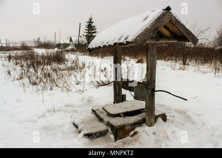 Rural landscape with views of the snowy Russian countryside and the well in the foreground Stock Photo