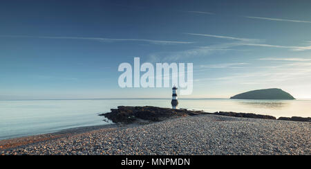 Panoramic view over marble beach with Penmon lighhouse and Puffin Island in background of Anglesey Island in North Wales, UK Stock Photo