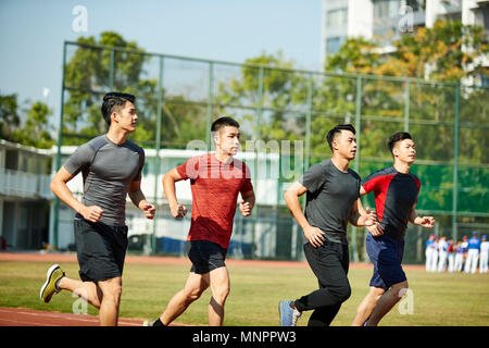 four asian young adults training running on track. Stock Photo