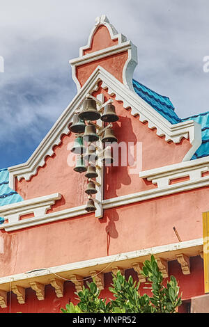 south american architecture with rusted bells or chimes on front of building in Aruba Stock Photo
