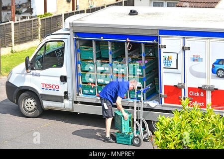 Side of open home food delivery van driver worker unloading online grocery shopping onto trolley from Tesco Supermarket residential street England UK Stock Photo