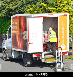 Sainsburys supermarket van driver man sorts online internet food grocery shopping order to place on trolley for customer home delivery service  UK Stock Photo