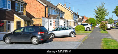 Street scene some semi detached houses paving over front garden with block paved driveway replacing house lawn for car parking space Essex England UK Stock Photo