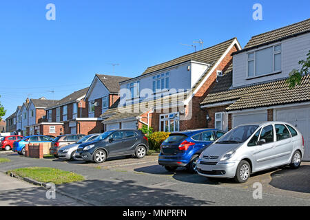 Suburb street scene row semi detached houses paving over front garden with paved driveway replacing house lawn for car parking space Essex England UK Stock Photo