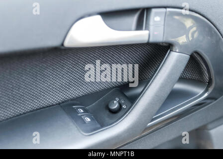 Close up shot of modern car door panel with windows and rear view mirrors controls and switches. Stock Photo