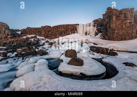 Partially frozen waterfall Öxarárfoss in winter, river Öxará, Pingvellir National Park, Golden Circle, South Iceland Stock Photo