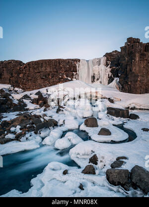 Partially frozen waterfall Öxarárfoss in winter, river Öxará, Pingvellir National Park, Golden Circle, South Iceland Stock Photo