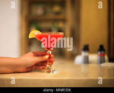 Strawberry margarita glass in womans hand on bar counter Stock Photo