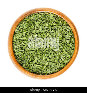 Dried chives in wooden bowl. Allium schoenoprasum. Chopped, green herb, made of the leaves, also called scapes, the plant stems. Isolated macro photo. Stock Photo