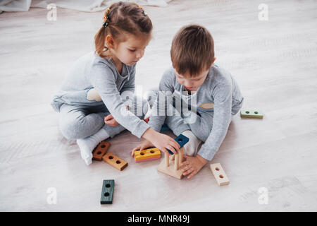 Children play with a toy designer on the floor of the children's room. Two kids playing with colorful blocks. Kindergarten educational games Stock Photo