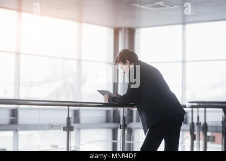 Back view of young confident man leader is resting after business meeting with foreign partners, while is standing near big office window background with copy space for your advertising text message Stock Photo