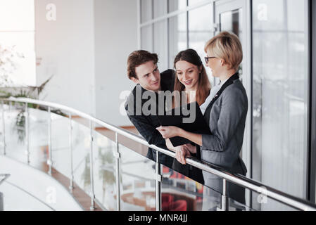 Young professional team. Group of young modern people in smart casual wear having a brainstorm meeting while standing behind the glass wall in the creative office Stock Photo