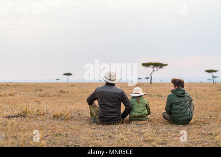 Family of father and kids on African safari vacation enjoying views over Masai Mara in Kenya Stock Photo