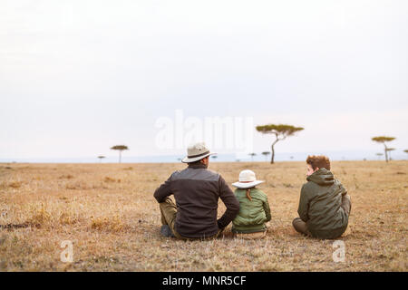 Family of father and kids on African safari vacation enjoying views over Masai Mara in Kenya Stock Photo