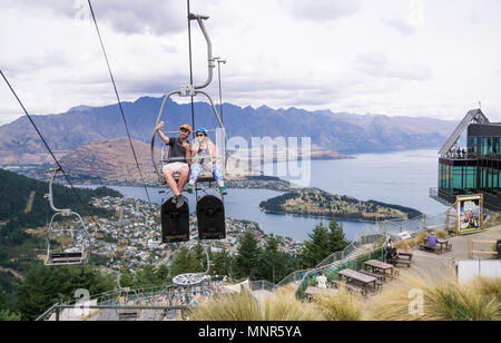 A young couple taking a selfie on the Skyline Gondola chairlift in Queenstown, NZ