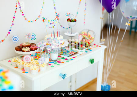 Cake, candies, marshmallows, cakepops, fruits and other sweets on dessert table at kids birthday party Stock Photo