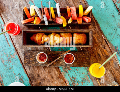 Top view of delicious organic food served for breakfast on rustic wooden table. Fruits,  juice,  croissants and jam flat lay. Stock Photo