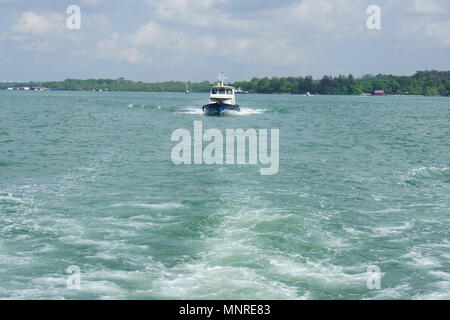 A Bum-boat captured sailing in middle of sea Stock Photo