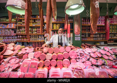 A smiling adult male merchant stands behind counter full of various types of meat for sale at Istanbul Spice bazaar in Turkey Stock Photo