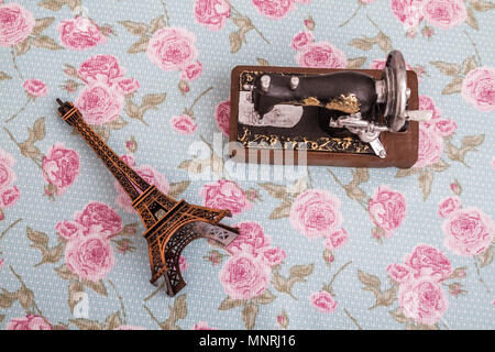 Statue model of eiffel tower and sewing machine on floral background Stock Photo