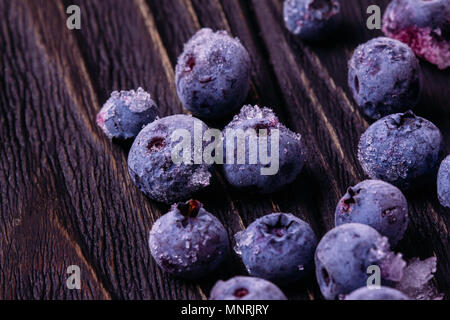 Blueberries berries close-up in a frost with ice on a wooden dark surface Stock Photo