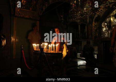 Jerusalem, Israel - May 16, 2018: A deeply religious woman lights candles in the Church of the Holy Sepulchre of Jerusalem to honor Jesus, the Son of  Stock Photo