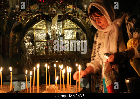 Jerusalem, Israel - May 16, 2018: A deeply religious woman lights candles in the Church of the Holy Sepulchre of Jerusalem to honor Jesus, the Son of  Stock Photo