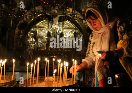 Jerusalem, Israel - May 16, 2018: A deeply religious woman lights candles in the Church of the Holy Sepulchre of Jerusalem to honor Jesus, the Son of  Stock Photo