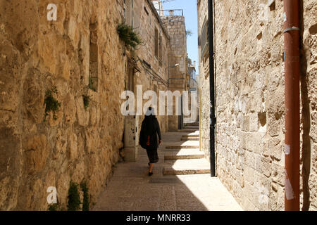 Jerusalem, Israel - May 16, 2018: A woman dressed in black walks in the midday sun through the old city of Jerusalem, Tel Aviv. Stock Photo