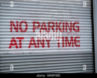 No parking at any time red spray painted warning sign on garage door Stock Photo