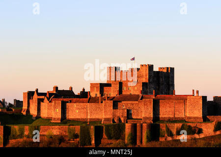 Dover castle, inner and outer walls seen early morning during Golden Hour just after sunrise. Union Jack flag flying over keep. Stock Photo