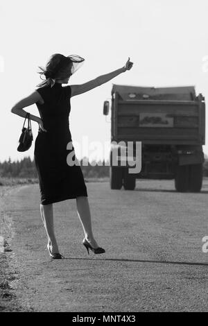 Laughing woman goes on the road against the background of a runner or car, the sunlight Stock Photo