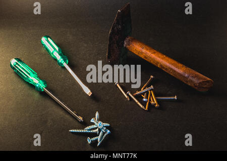 Screwdrivers, screws, nails and hammer on dark grey background Stock Photo