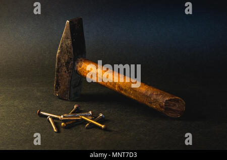 Wooden hammer and nails on dark grey background Stock Photo