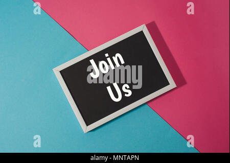 Join us - text on chalkboard on blue and pink bright background. Stock Photo