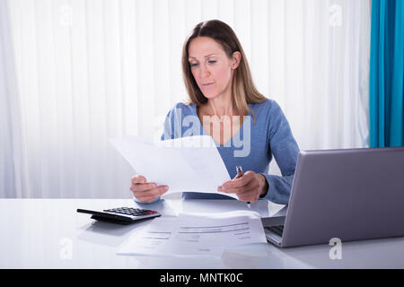 Close-up Of Mature Woman Analyzing The Invoice At Workplace Stock Photo