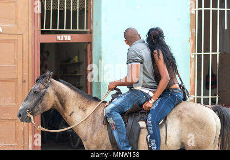 A couple ride their horse in Trinidad, Cuba stopping in front of the local bakery Stock Photo
