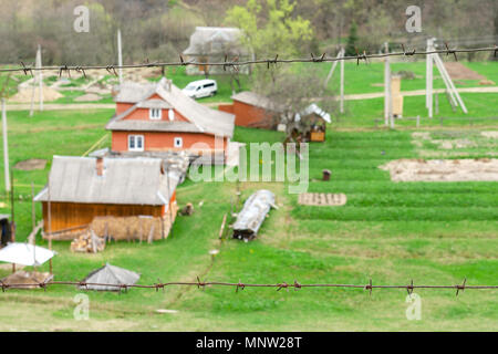 Old-fashioned wooden houses on the outskirts of the forest. Fenced with barbed wire. Among the Carpathian mountains in Ukraine. Selective focus. Art b Stock Photo