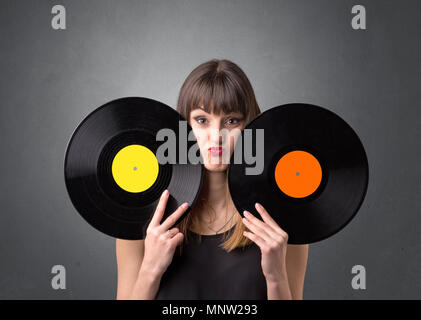 Young lady holding vinyl record on a grey background Stock Photo